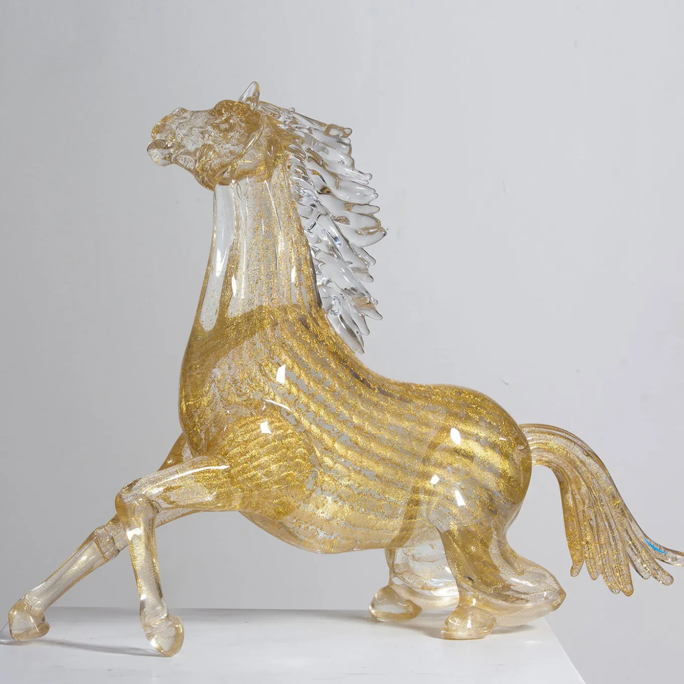 Piccolo cavallo seduto in vetro dorato